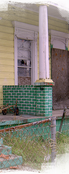 A yellow and green home is still boarded and vacant more than a year after Katrina 239x600